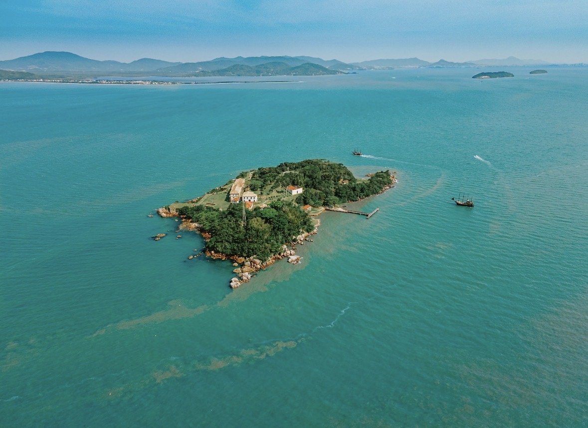Vista real da Ilha de Anhatomirim cercada pelo mar